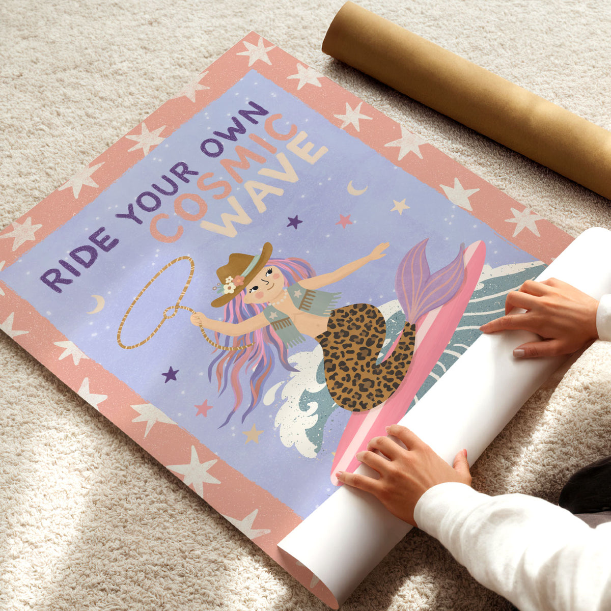 Illustrated poster of a cowgirl mermaid surfing a wave with a lasso under the words ride your own cosmic wave