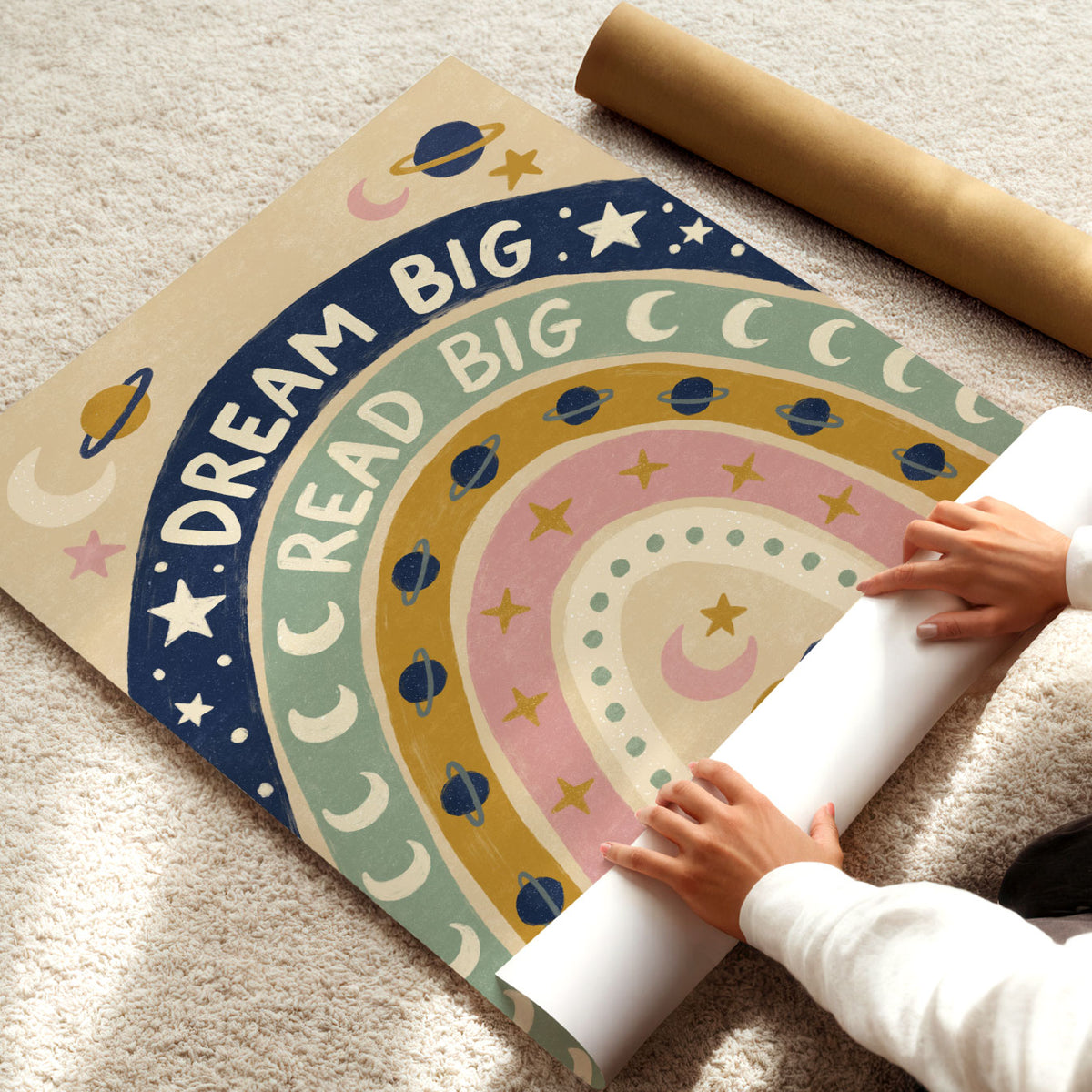 Illustrated poster of a rainbow filled with planets and stars lettered dream big read big
