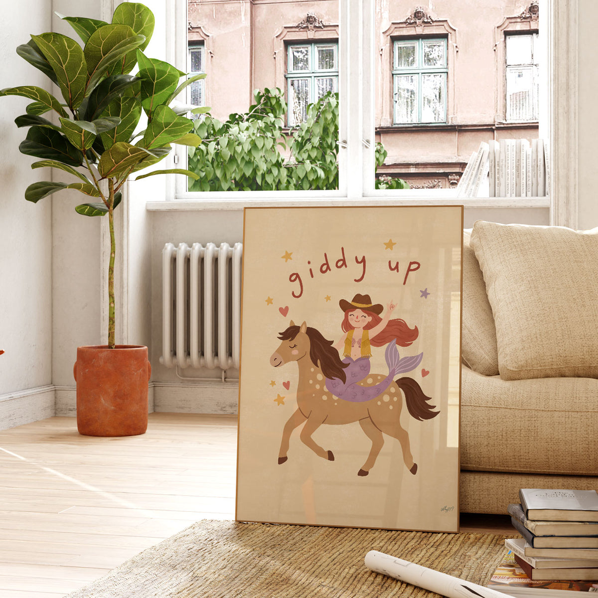 Illustrated mermaid in a cowboy hat and fringed vest riding a spotted horse, with hand-lettered giddy up above, on a cream background.