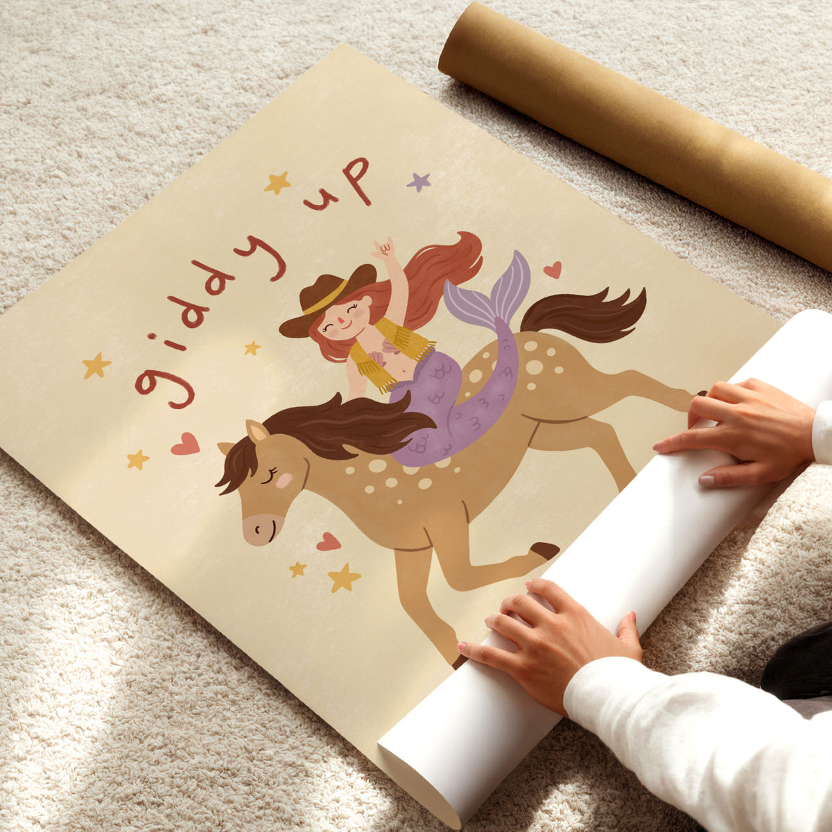 Illustrated mermaid in a cowboy hat and fringed vest riding a spotted horse, with hand-lettered giddy up above, on a cream background.