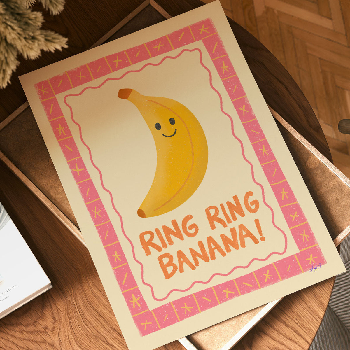 Funny banana wall art featuring a cheerful banana character surrounded by a pink patterned border.